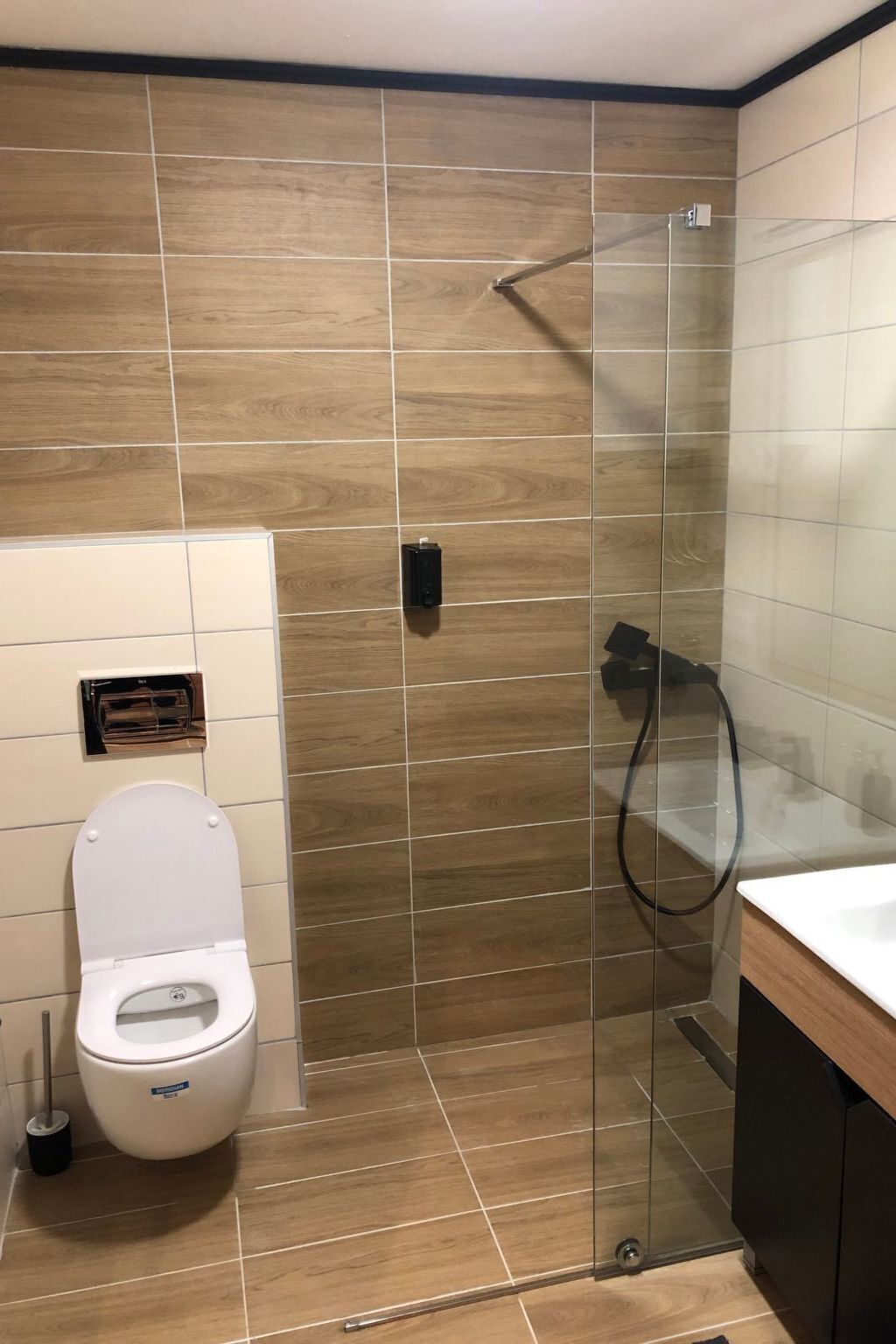 Un baño moderno con inodoro, cabina de ducha de vidrio y lavamanos.