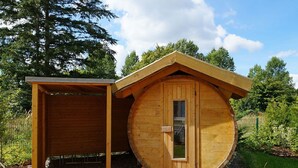 Una cabaña de madera con una puerta circular y una caseta separada.