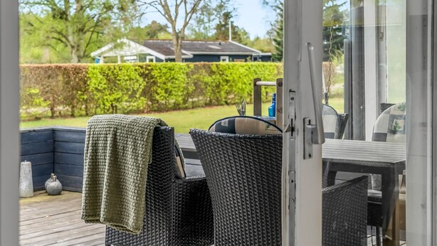 Eine Terrasse im Freien mit Korbmöbeln, einem Grill und Blick auf eine Wohngegend.