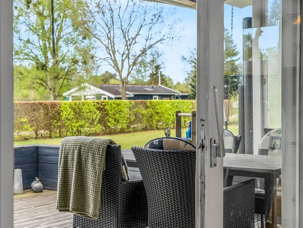 Un patio al aire libre con mobiliario de mimbre, una parrilla y vistas a un barrio residencial.