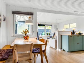 Una cocina moderna con armarios de madera, un comedor con mesa y sillas, y vistas al exterior.
