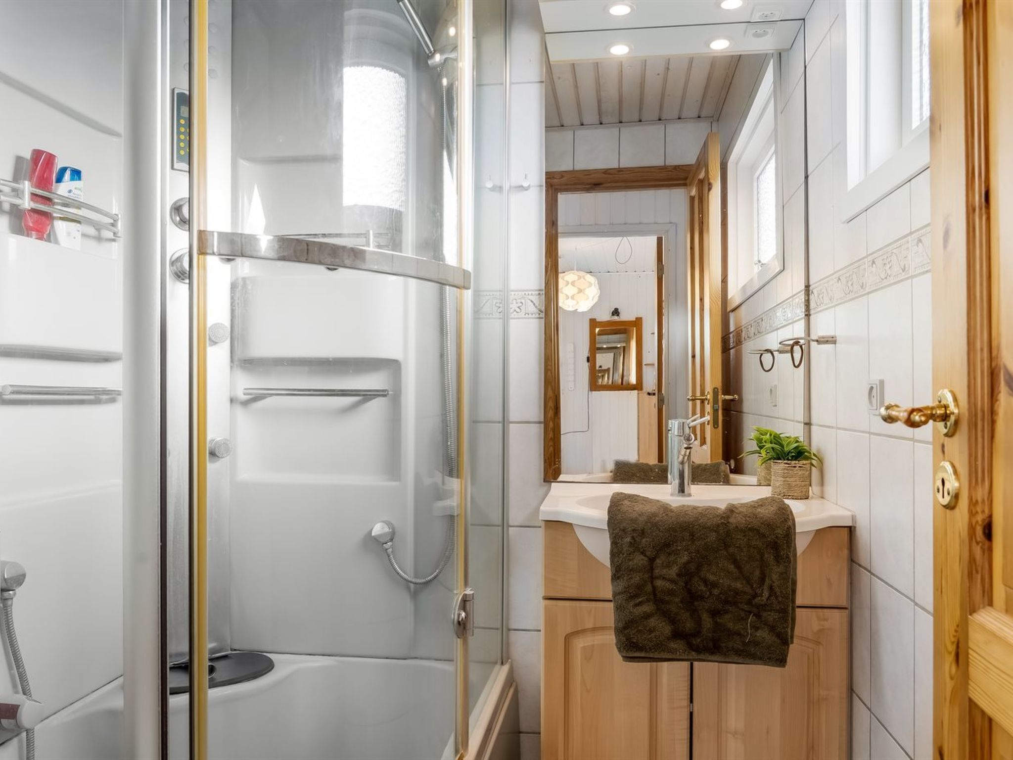 Un bany modern amb una cabina de dutxa de vidre, un moble de tocador de fusta i un mirall sobre el lavabo.