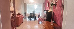 En matplats med ett bord och stolar, ett träskåp och en vas med blommor.