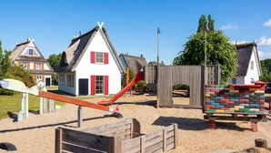 Une aire de jeux avec une balançoire, un bac à sable et des structures de jeu en bois.