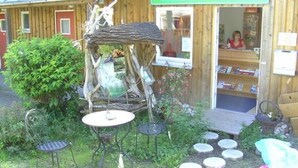 Ein Holzbauten mit einer Rezeption, einer kleinen Außenbereichssitzgelegenheit mit Tischen und Stühlen sowie einem dekorativen Gartenbrunnen.
