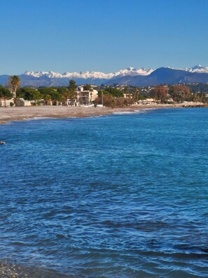 Un paysage côtier offrant une vue dégagée sur la mer, une plage et une chaîne de montagnes en arrière-plan.