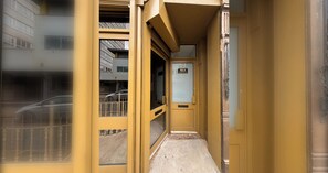 Un couloir étroit avec une porte jaune portant l’inscription « 65A », qui donne accès à une pièce.