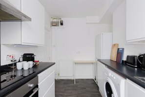 Une cuisine compacte équipée d’une cuisinière, d’un four à micro-ondes et d’un lave-linge.
