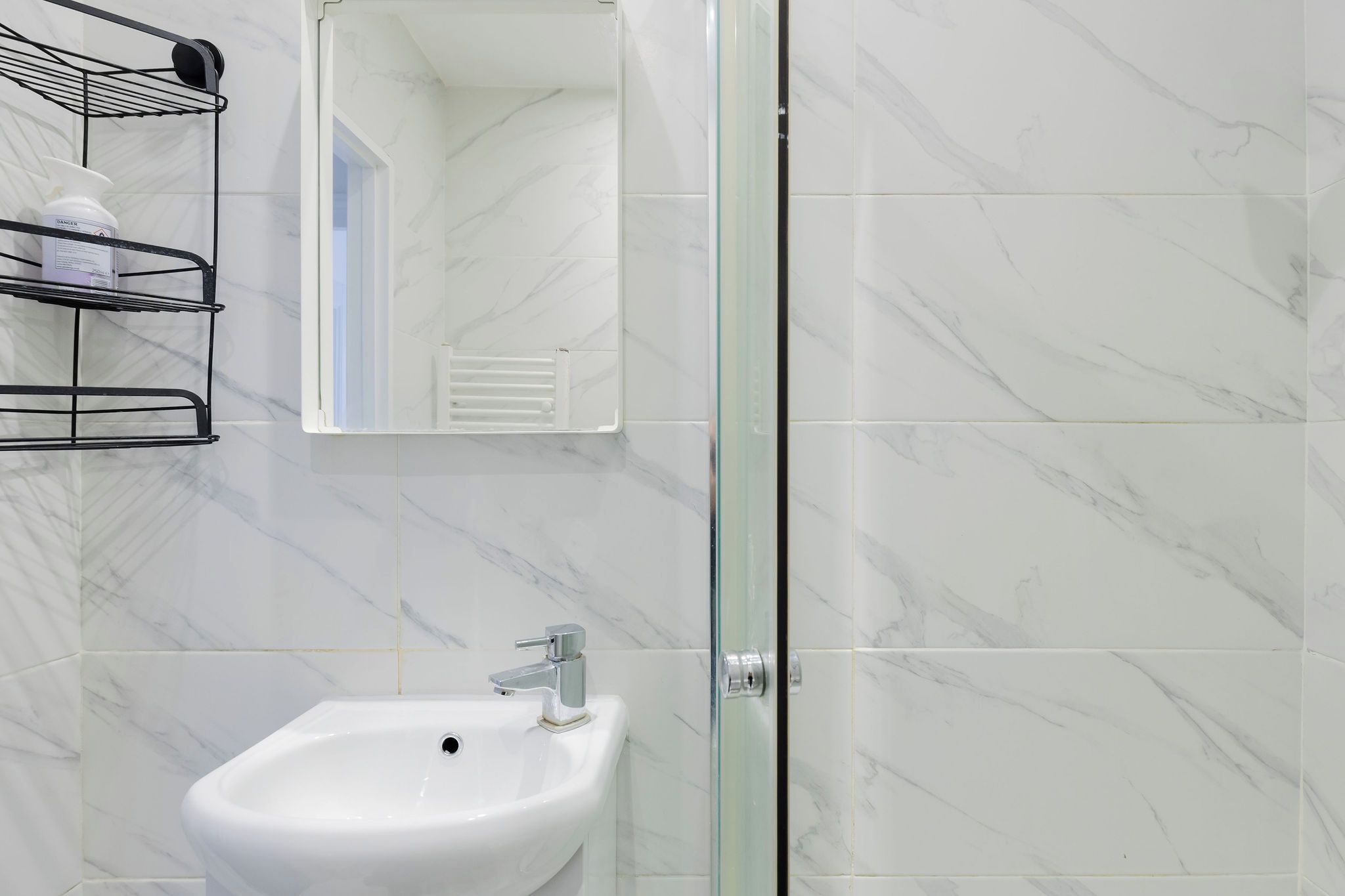 A bathroom with a white sink, a mirror, and a shower with glass doors.