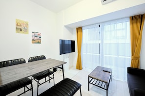 A modern room with a dining table, chairs, a TV, and a sofa. - CREST Nishijin (Fukuoka)