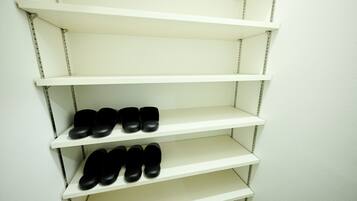 A set of white shelves with black shoes on the bottom shelf.