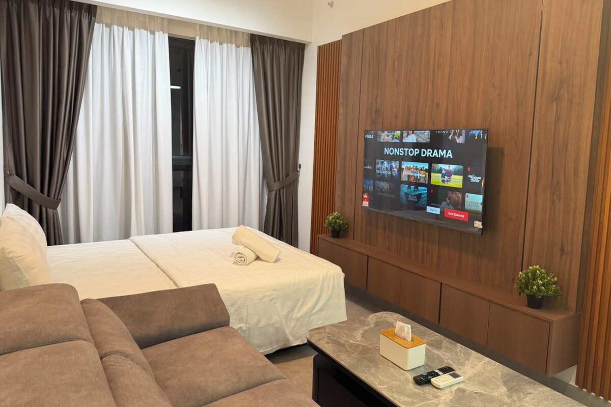 Een hotelkamer met een bed, een bank, een aan de muur bevestigde televisie en een kleine tafel met een afstandsbediening.