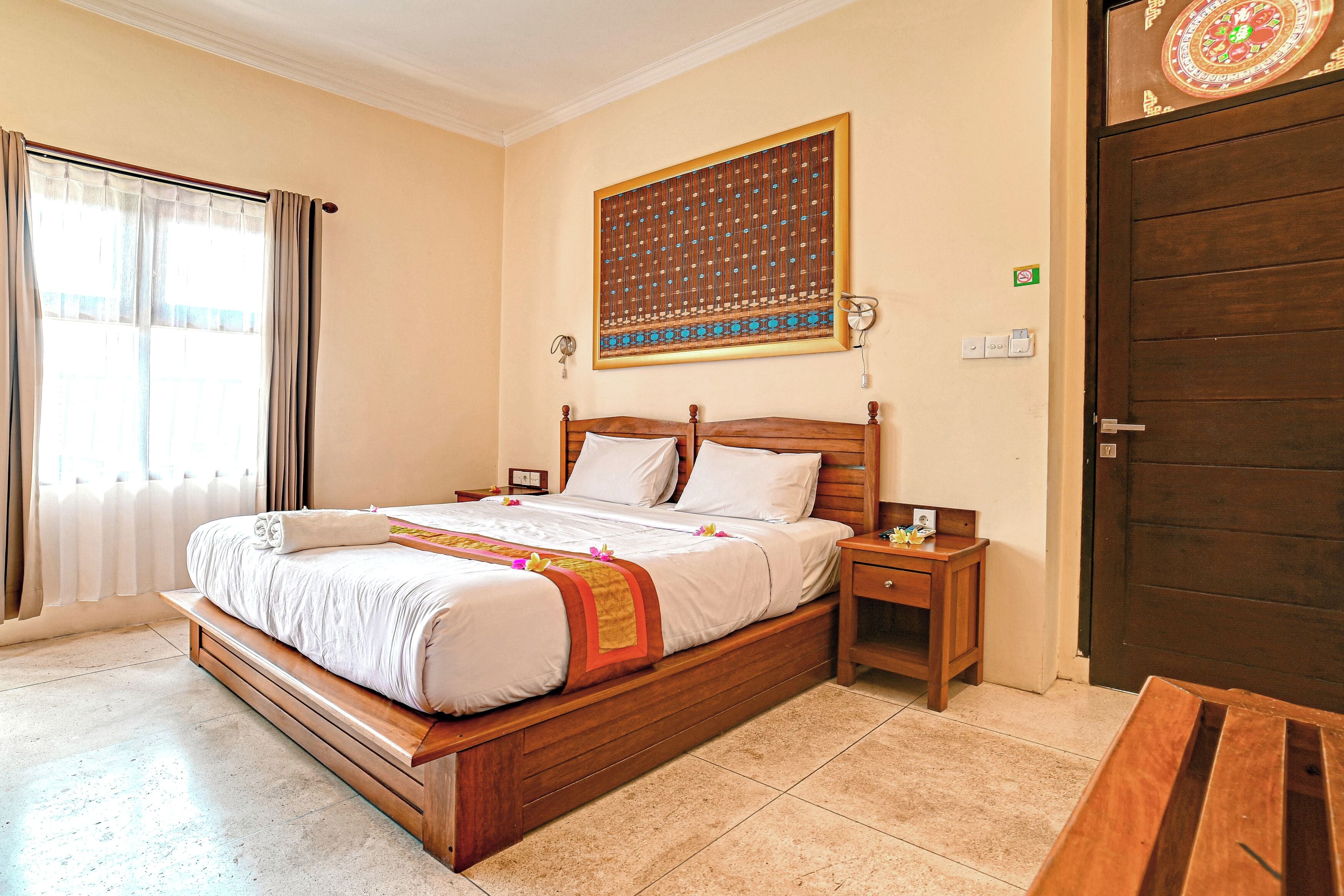 Cama bem arrumada com cabeceira de madeira, mesa de cabeceira e uma obra de arte na parede.