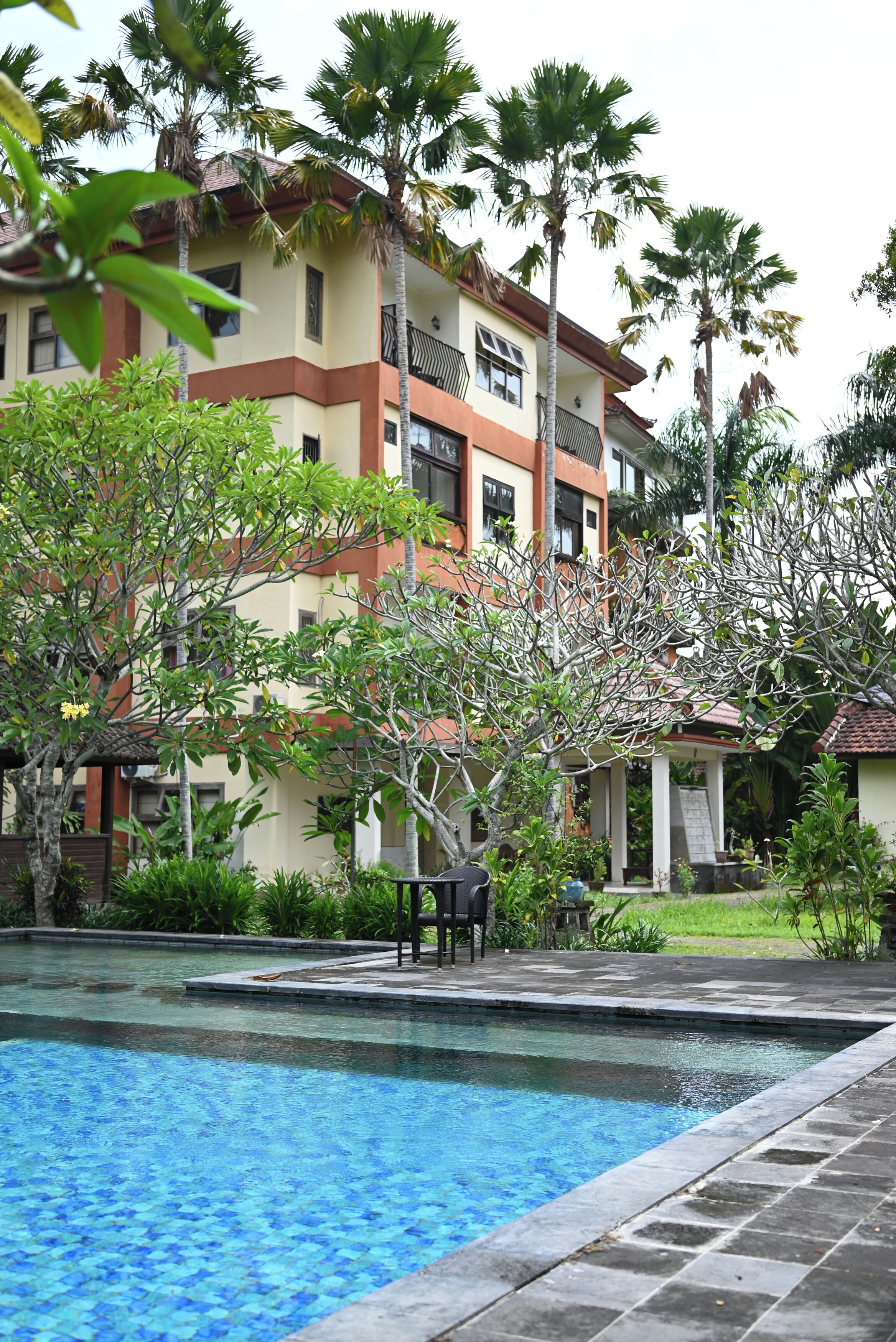 Un hôtel doté d’une piscine entourée de palmiers et de verdure.