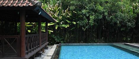 A rectangular swimming pool with a tiled deck area adjacent to it.