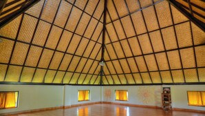 A spacious room with a high, thatched ceiling and wooden flooring. - Suly Resort Ubud (Ubud)