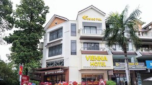Hotel Viena con una cafetería visible y una exhibición floral en el exterior.