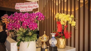 Un mostrador de recepción con un cartel que anuncia un evento hotelero, plantas en macetas y un trofeo.