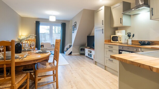 Una cocina moderna con comedor, muebles de madera y un microondas empotrado.