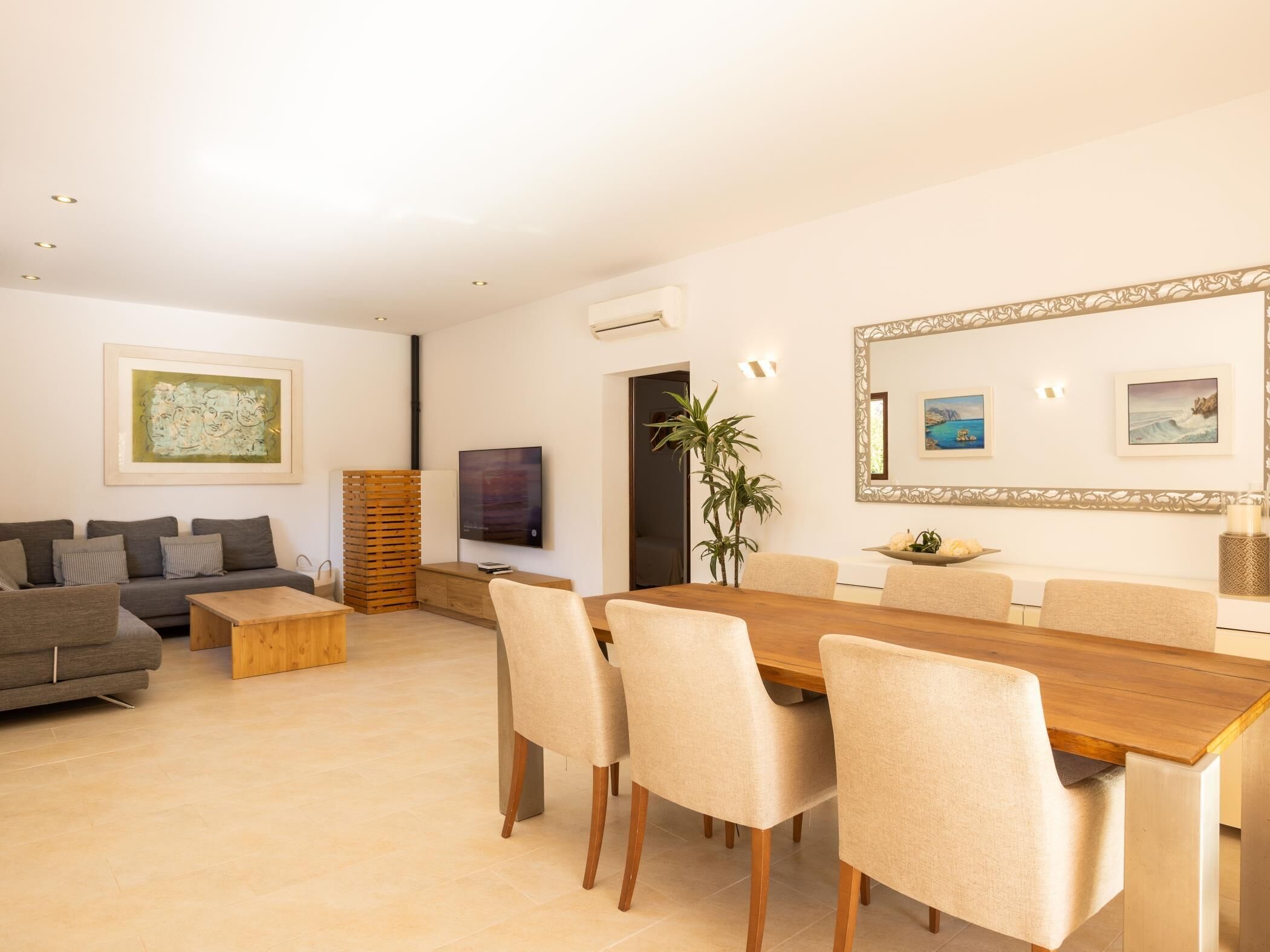 Een moderne woonkamer met een bank, salontafel en een eethoek met stoelen en een houten tafel.