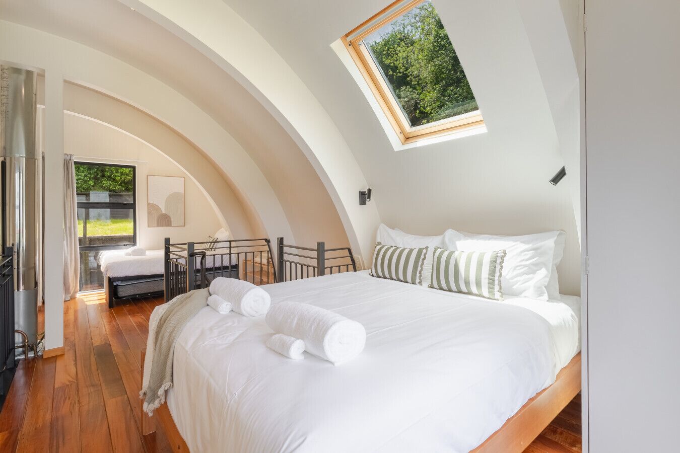 Une chambre avec un grand lit, une lucarne et une vue sur la verdure.