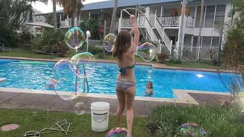 A swimming pool with bubbles, a person in a bikini, and a house in the background.