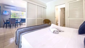 Een hotelkamer met een bed, een televisie, een zithoek met stoelen en uitzicht op het omliggende landschap.