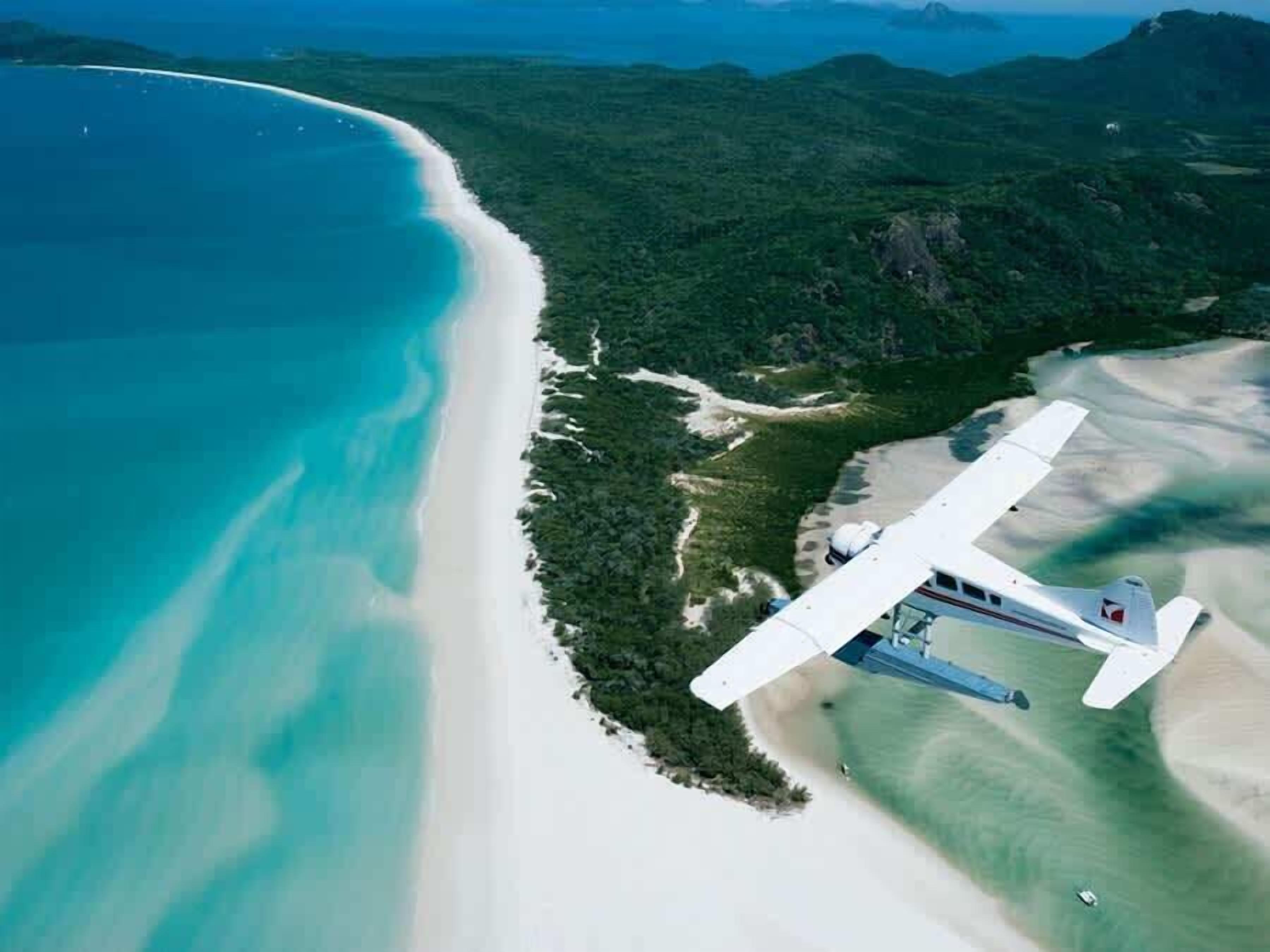 An aerial view of a beach with a small airplane on the sand.
