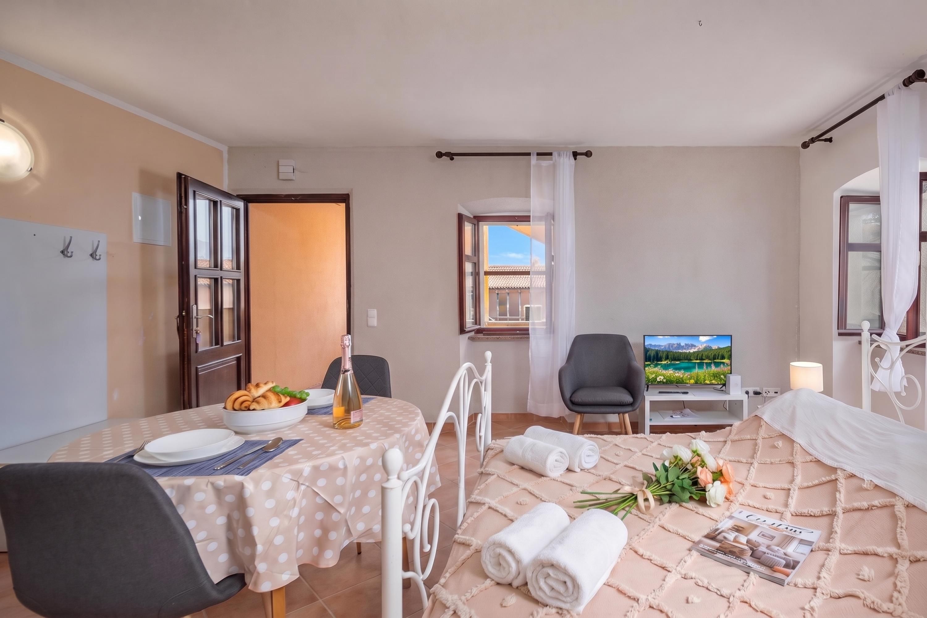 Een hotelkamer met een eethoek, een bed, een televisie en uitzicht op het landschap.