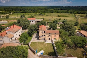 A residential area with houses, a stone wall, and a grassy field. - Iva Apartments (Bale)