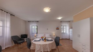 Un coin repas comprenant une table ronde, des chaises, un téléviseur et un meuble.