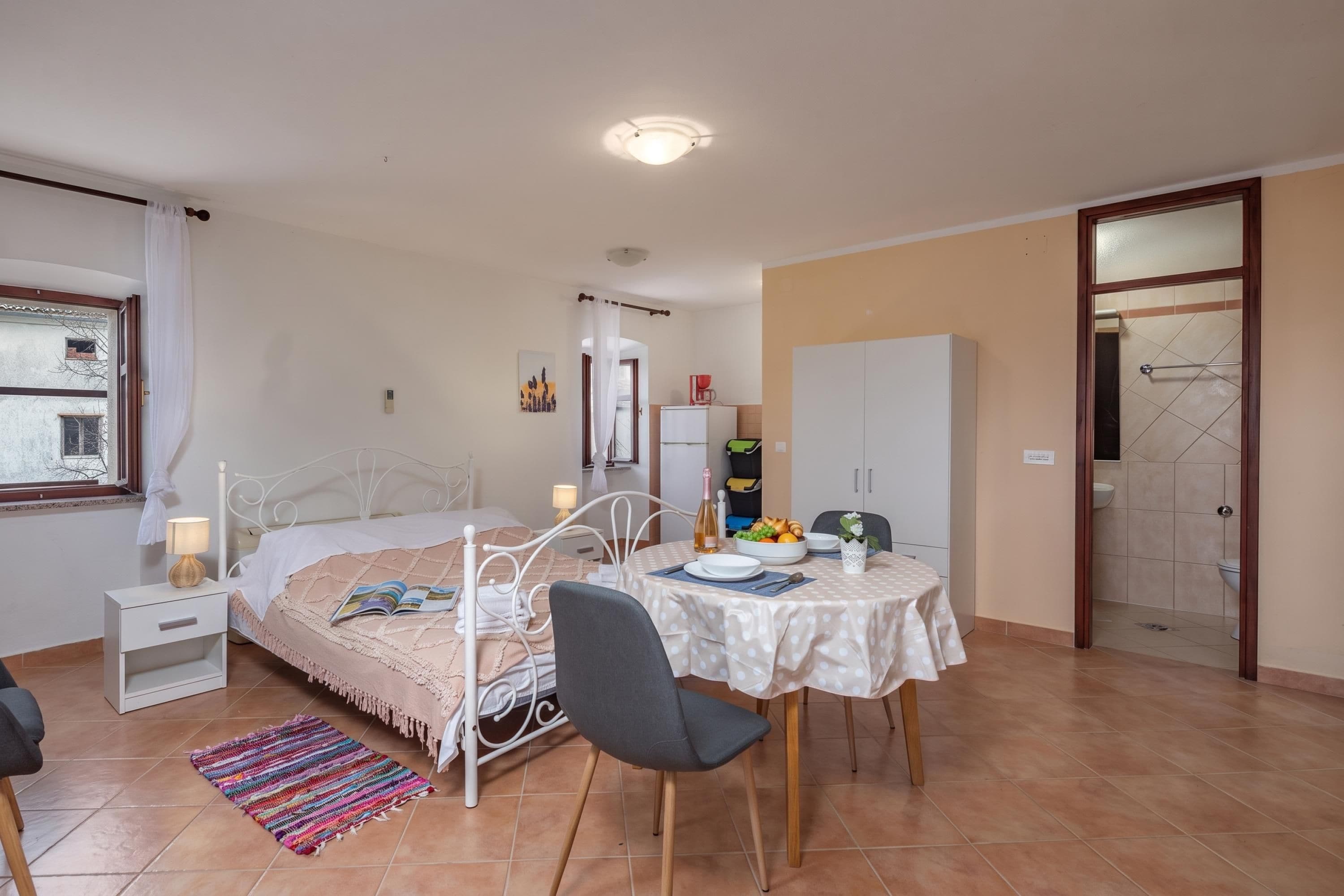 Un dormitorio con cama, mesita de noche, lámpara y ventana con cortinas.