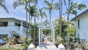 A wooden pathway leading to a white gazebo surrounded by lush greenery and palm trees. - Whitsundays Mango Studio with Pool & Gardens (Airlie Beach)
