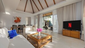 A spacious living room with a large TV, a wooden coffee table, and a sofa. - Modern 3BR Villa Kaimana Private Pool (Thep Krasattri)