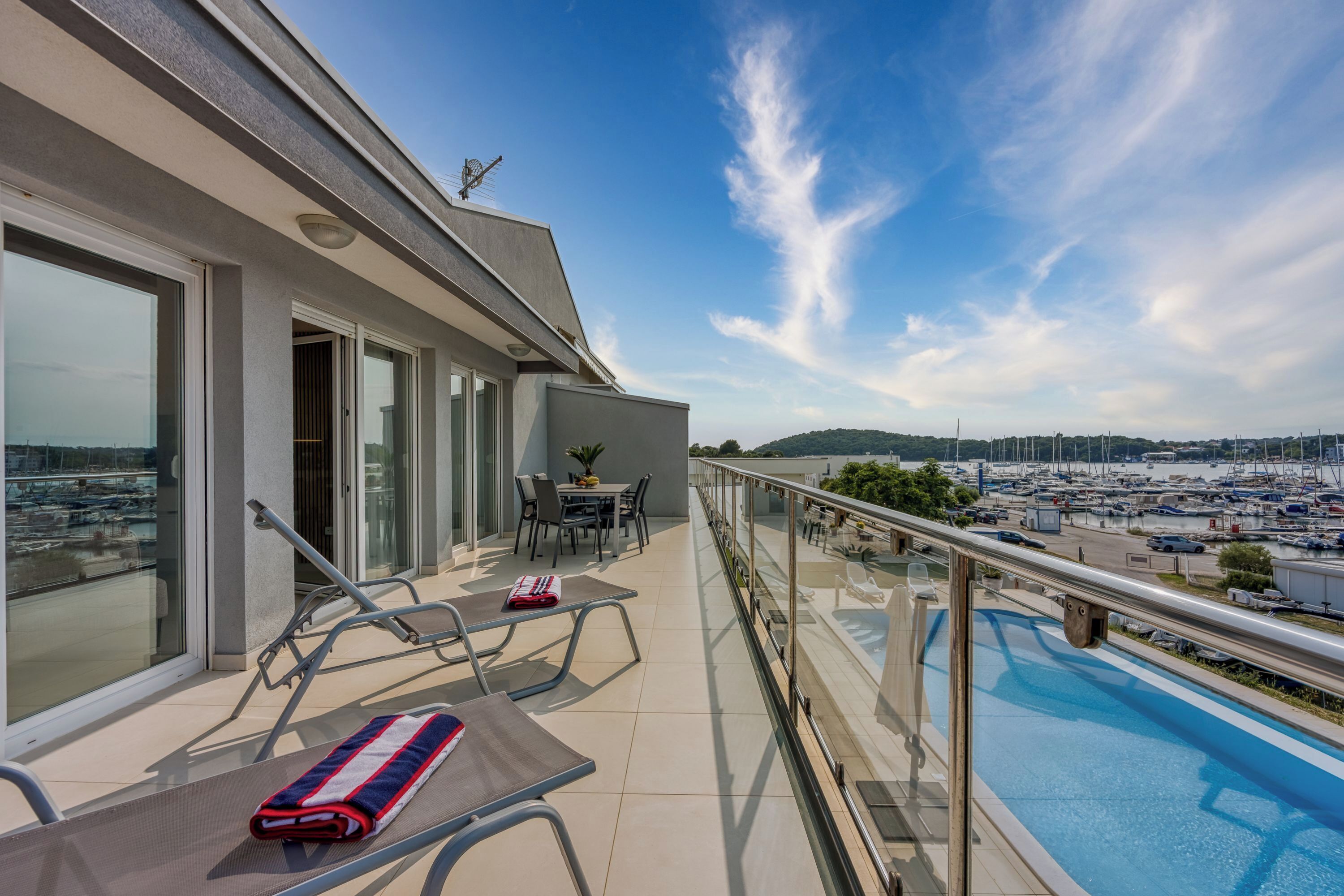 A balcony with a pool, glass doors, and a table with chairs.