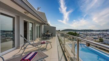 A balcony with a pool, glass doors, and a table with chairs.