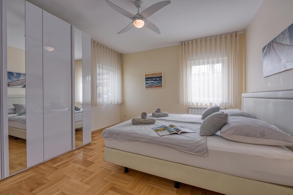 Une chambre à coucher moderne avec un lit, un ventilateur de plafond et un grand miroir.
