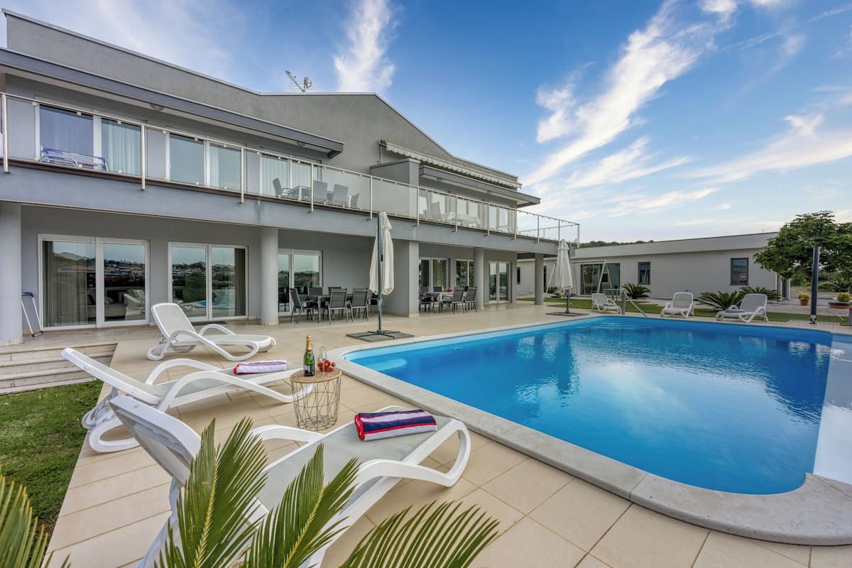 A modern house with a swimming pool, outdoor seating, and a balcony.