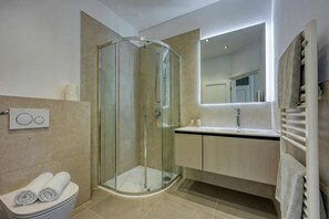 A modern bathroom with a glass-enclosed shower, a toilet, a sink, and a towel rack. - Elegant Panoramic Seaview Apartments (Medulin)