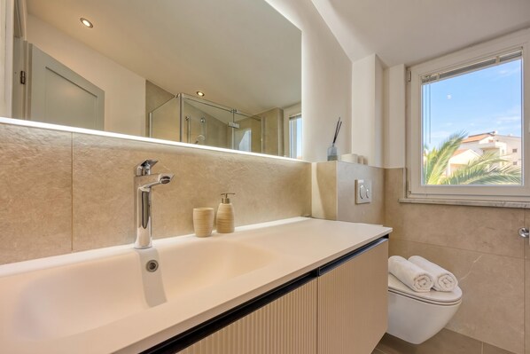 Une salle de bain moderne avec un grand miroir, une baignoire et des toilettes.