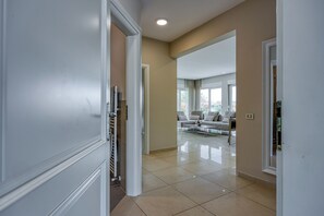 Um corredor espaçoso com design moderno, que dá acesso a uma sala de estar com sofá e mesa de centro.