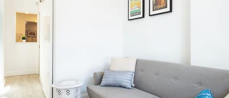 A modern living room with a grey sofa, a small round table, and two framed pictures on the wall.