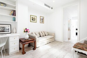 Een moderne woonkamer met een bank, een klein tafeltje met een vaas en een bureau met lades.