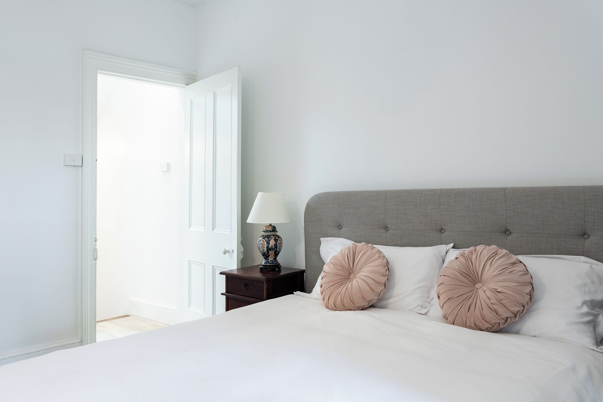 A bedroom with a bed, a nightstand, a lamp, and a door.