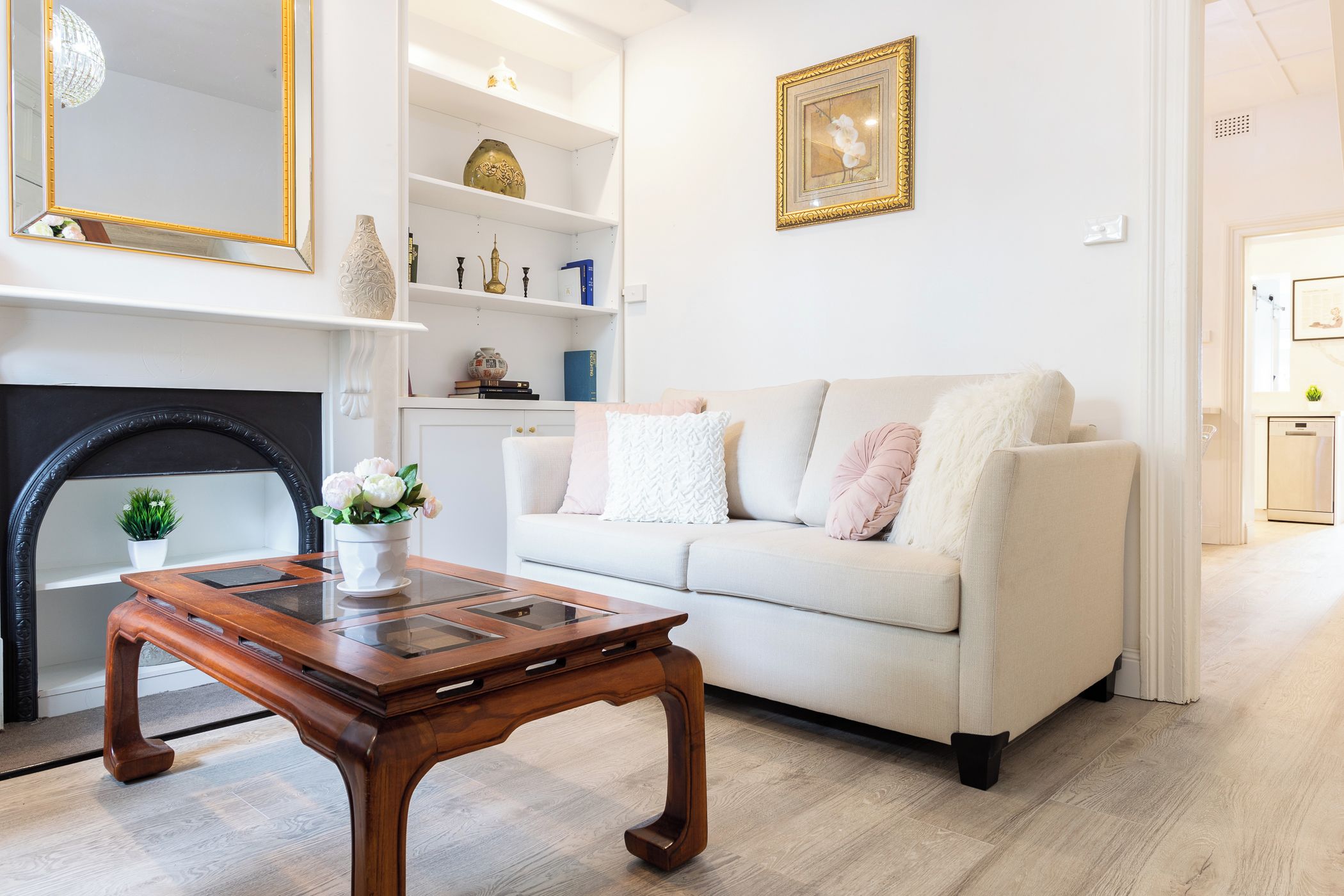 A living room with a sofa, a coffee table, a fireplace, and a bookshelf.