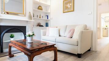A living room with a sofa, a coffee table, a fireplace, and a bookshelf.