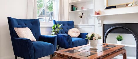 Una habitación con dos sillones azules, una mesa de centro de madera y una chimenea.