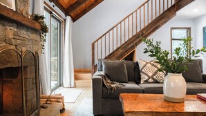 Ein gemütliches Wohnzimmer mit Kamin, einer Couch, einem Couchtisch und einer Treppe.