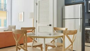 A modern kitchen with a refrigerator, cabinets, and a dining area with a table and chairs.