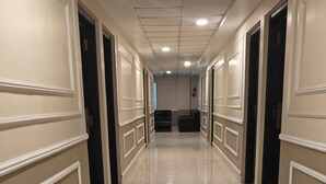 A long, narrow hallway with marble flooring and cream-colored walls with decorative molding. - Galleria Hotel Ajmer (Ajmer)